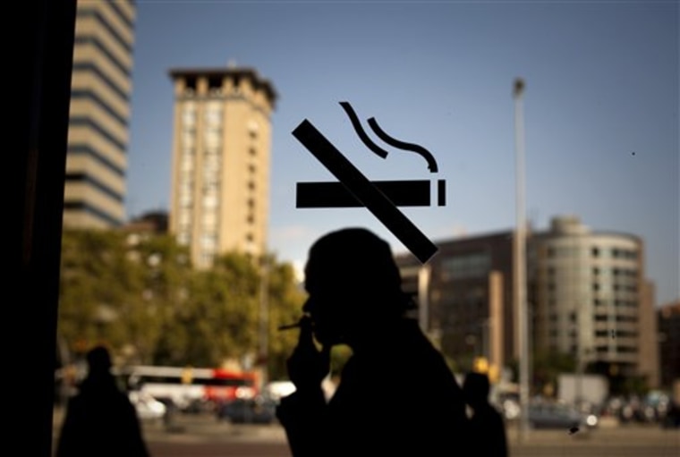 A man smokes, as he is seen through the glass of a window in a train station in Barcelona, Spain, on Wednesday. Spain, a country famed for its smoke-filled bars, corner cafes and restaurants, is poised to enact a tough new anti-smoking law eliminating its status as Western Europe's last country where lighting up in indoor public places is allowed. 